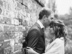 bride and groom kiss by wall